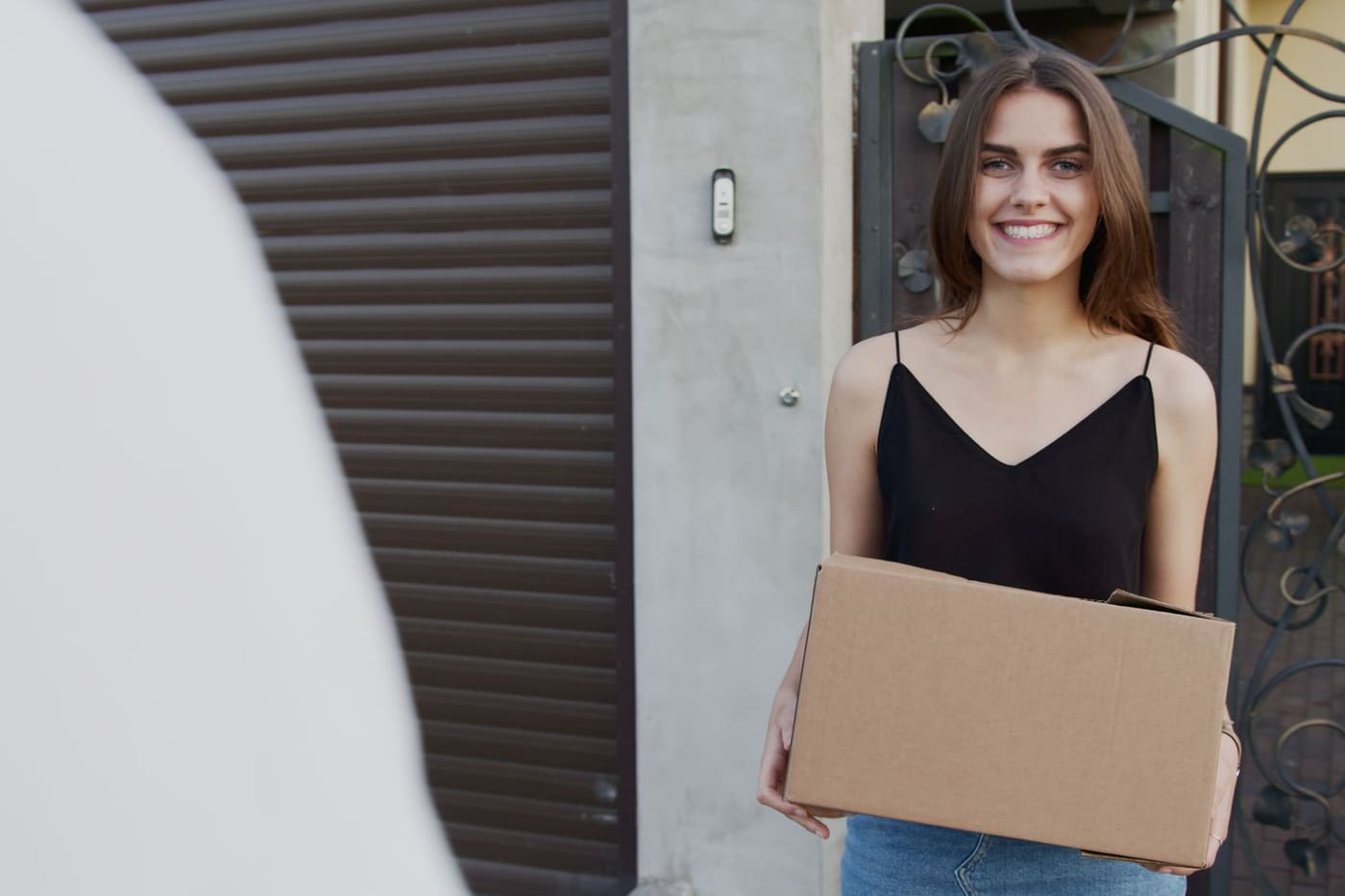 A smiling customer holding a delivered box at her front door