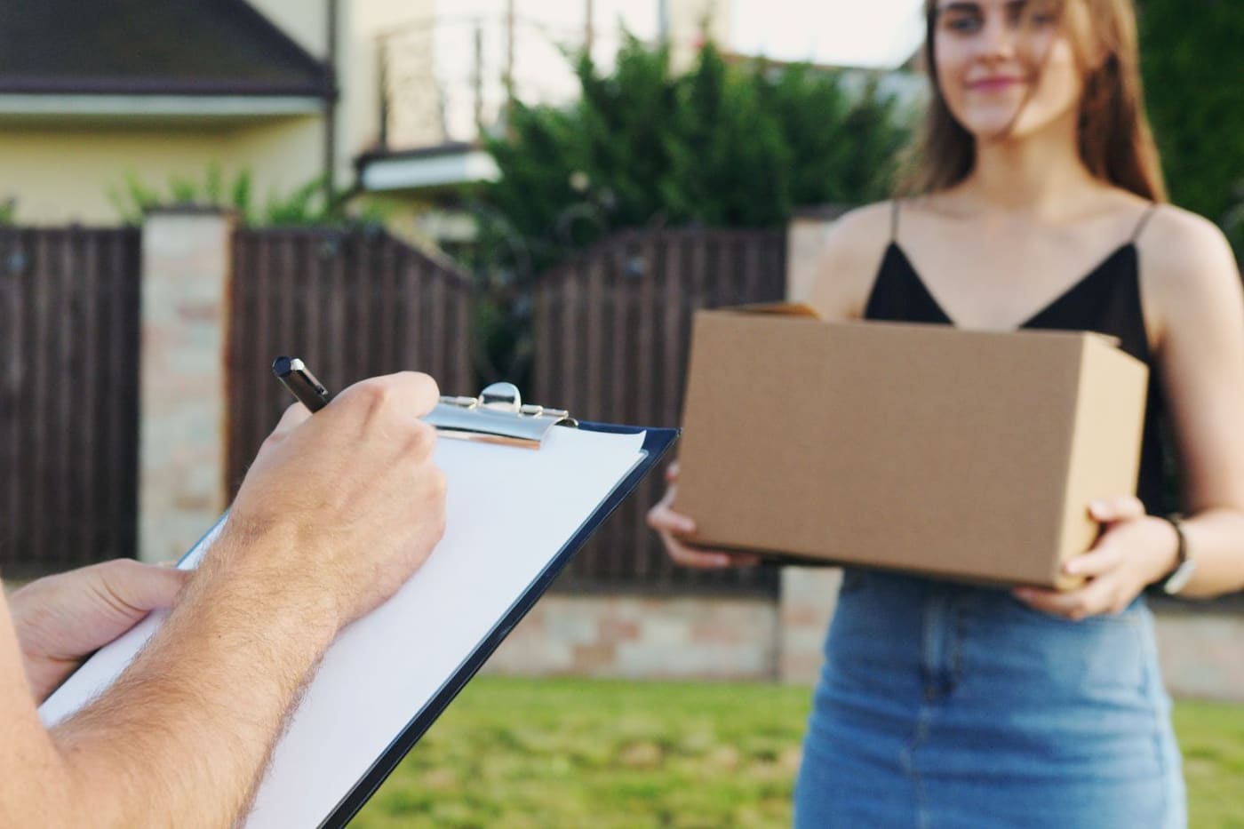 A customer holding a box while the inventory is checked off on a clipboard outside the house